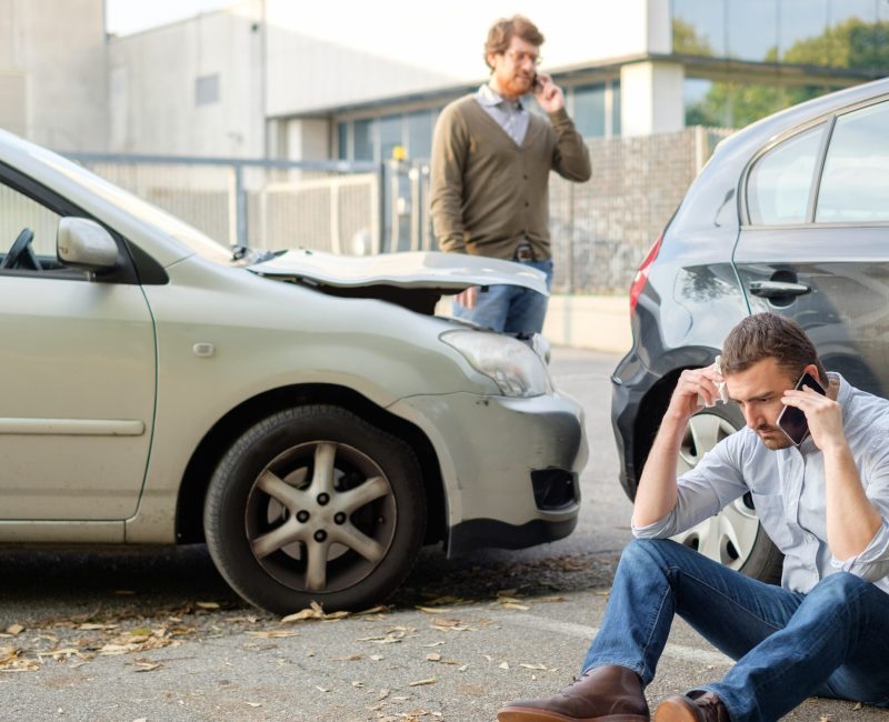 Two men calling car help assistance after an accident