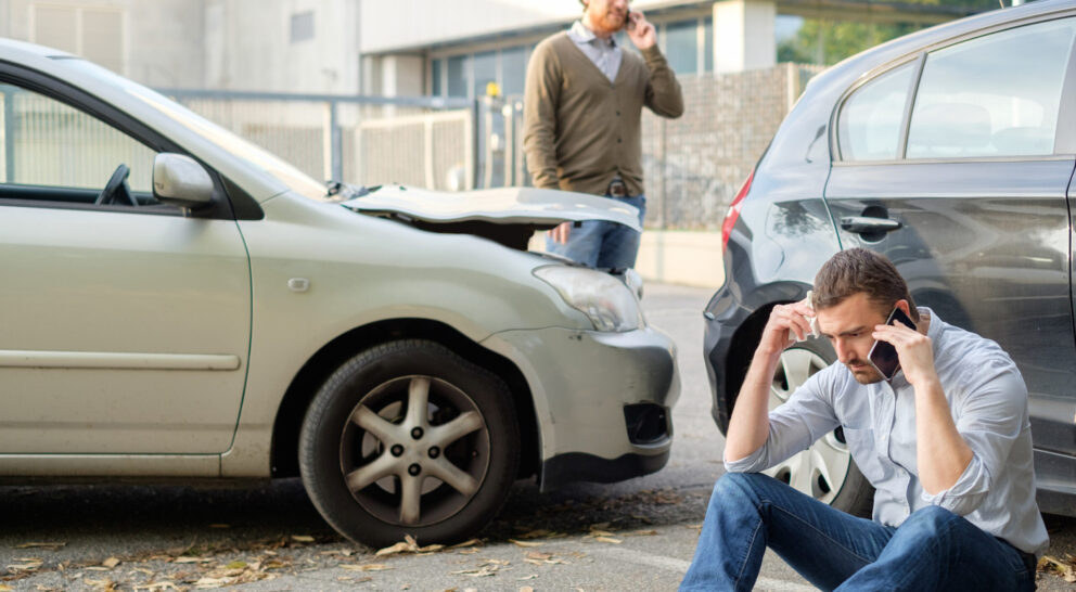 Two men calling car help assistance after an accident